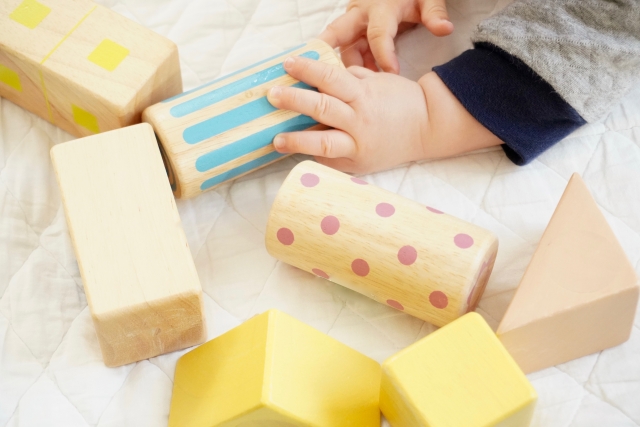 キッズ・ラボラトリーやCha Cha Chaでレンタルできる出産祝いに人気のおしゃれな木製の積み木で遊ぶ赤ちゃんの手