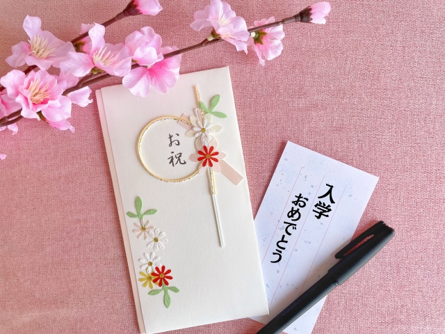 入学祝いの相場とマナーを解説。桜とのし袋のイメージ。